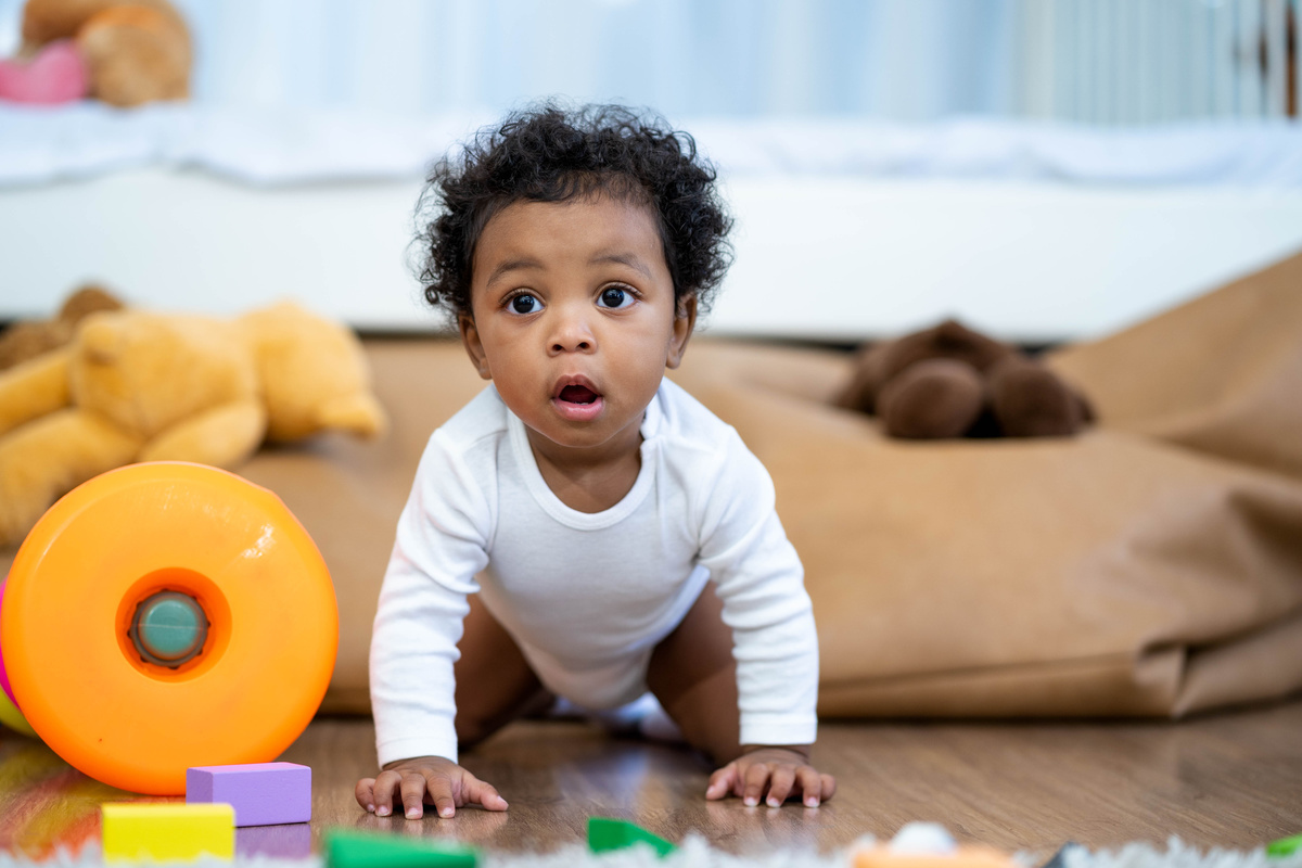 Little Baby Boy Crawling on Wooden Floor with Toys