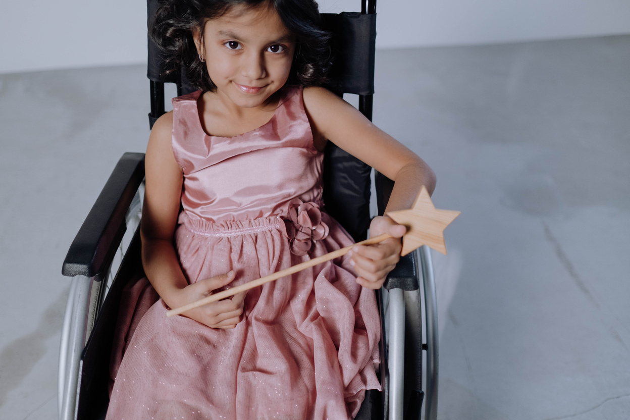A Girl in Pink Dress Sitting on Black Wheelchair